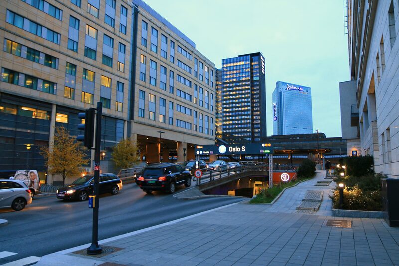 City street near Oslo S central station with cars, traffic signs, and tram infrastructure