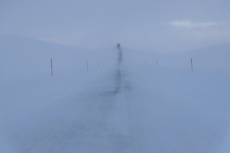 Winter road on the Båtsfjordfjellet mountain plateau in northern Norway — snow-covered landscape in a blizzard